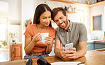 Young content interracial couple using a phone together at home. Happy caucasian boyfriend and mixed race girlfriend using social media on a cellphone. Happy husband and wife relaxing and spending time together in the morning