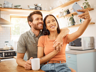 Buy stock photo Young cheerful interracial couple taking a selfie with a phone together at home. Joyful caucasian boyfriend and mixed race girlfriend taking a photo on a cellphone. Happy husband and wife relaxing and spending time together in the morning