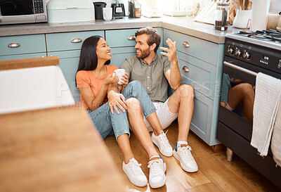 Buy stock photo Happy interracial couple bonding while drinking coffee together at home. Loving caucasian boyfriend and mixed race girlfriend sitting on the kitchen floor. Content husband and wife relaxing and spending time together in the morning