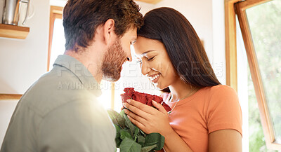 Young content caucasian boyfriend giving his mixed race girlfriend a bouquet of flowers at home. Happy hispanic wife receiving roses from her husband. Interracial couple relaxing together at home