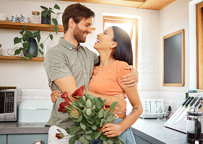 Buy stock photo Young content caucasian boyfriend hugging his mixed race girlfriend after giving her a bouquet of flowers at home. Happy hispanic wife receiving roses from her husband. Interracial couple bonding together at home