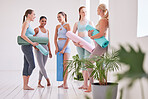 Happy women talking before yoga class. Group of friends bonding before yoga workout. Dedicated women ready for yoga exercise. Friends being social before yoga practice in the studio
