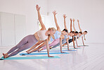 Group of women in balancing yoga pose. Group of fit women in yoga practice. Women stretching during pilates class. Women balancing side plank in yoga exercise. Group of women exercise together