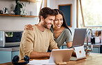Beautiful young hispanic wife standing behind her caucasian husband working on his laptop while they look at the screen together and smile. Happy young interracial couple surfing the internet, looking at home finances and enjoying work from home