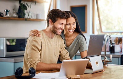 Beautiful young hispanic wife standing behind her caucasian husband working on his laptop while they look at the screen together and smile. Happy young interracial couple surfing the internet, looking at home finances and enjoying work from home
