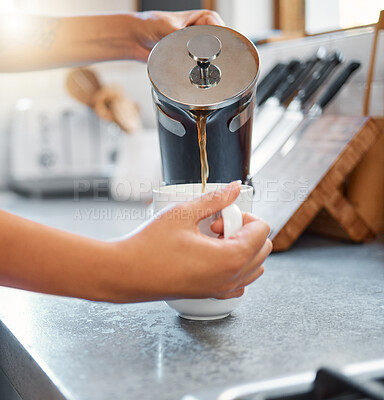 Close up of female hands pouring coffee into a cup standing at a kitchen counter. Unrecognizable person having a cup of coffee in the morning at home