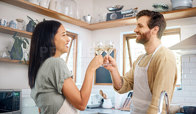 Buy stock photo Young interracial couple sharing toast with wine glasses while wearing aprons and cooking together in kitchen at home. Young couple enjoying romantic homemade dinner for date night at home