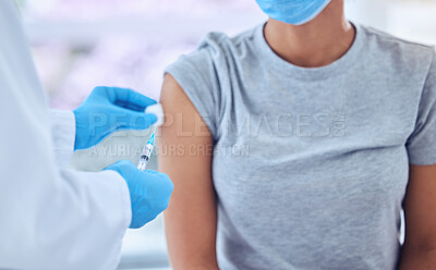 Doctor wiping the arm of a patient with cotton ball. Doctor preparing a patient for injection with covid vaccine. Doctor holding a needle with corona virus antidote cropped