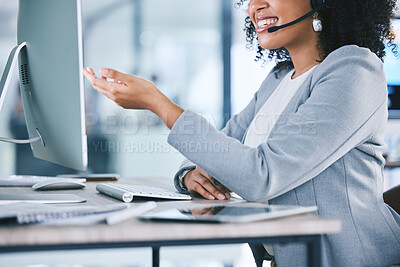 Closeup of one happy young mixed race call centre telemarketing agent talking on a headset while working on a computer in an office. Confident friendly female consultant operating helpdesk for customer service and sales support