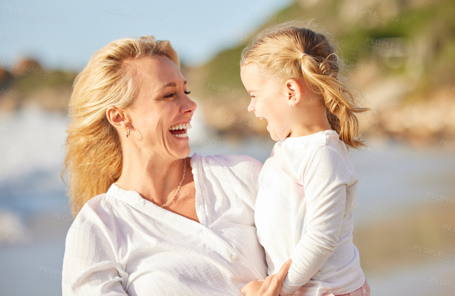 Buy stock photo Closeup of a caucasian girl laughing while enjoying a day out with her mother at the beach. Mom and daughter enjoying a summer vacation by the sea. Enjoying family time while on holiday