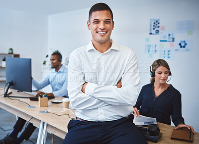 Buy stock photo Portrait of confident young mixed race call centre telemarketing agent standing with arms crossed while working in a call centre with colleagues in the background. Happy male manager and supervisor operating helpdesk for customer service and sales support
