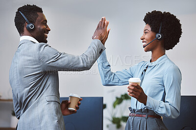 Buy stock photo Two happy african american call centre telemarketing agents giving each other a high five and cheering with joy while drinking coffee in an office. Excited and ambitious consultants celebrating successful sales targets and winning victory