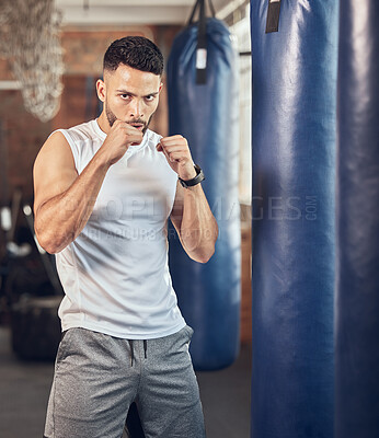 Strong boxer ready to punch in the gym. Portrait of mma fighter ready for cardio combat. Boxer working out with punching bag. Bodybuilder using equipment for boxing routine.