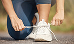 Closeup of one mixed race woman tying her shoelaces while exercising outdoors. Athlete fastening sneaker footwear for a comfortable fit and to prevent tripping while getting ready for cardio training workout or run at the park