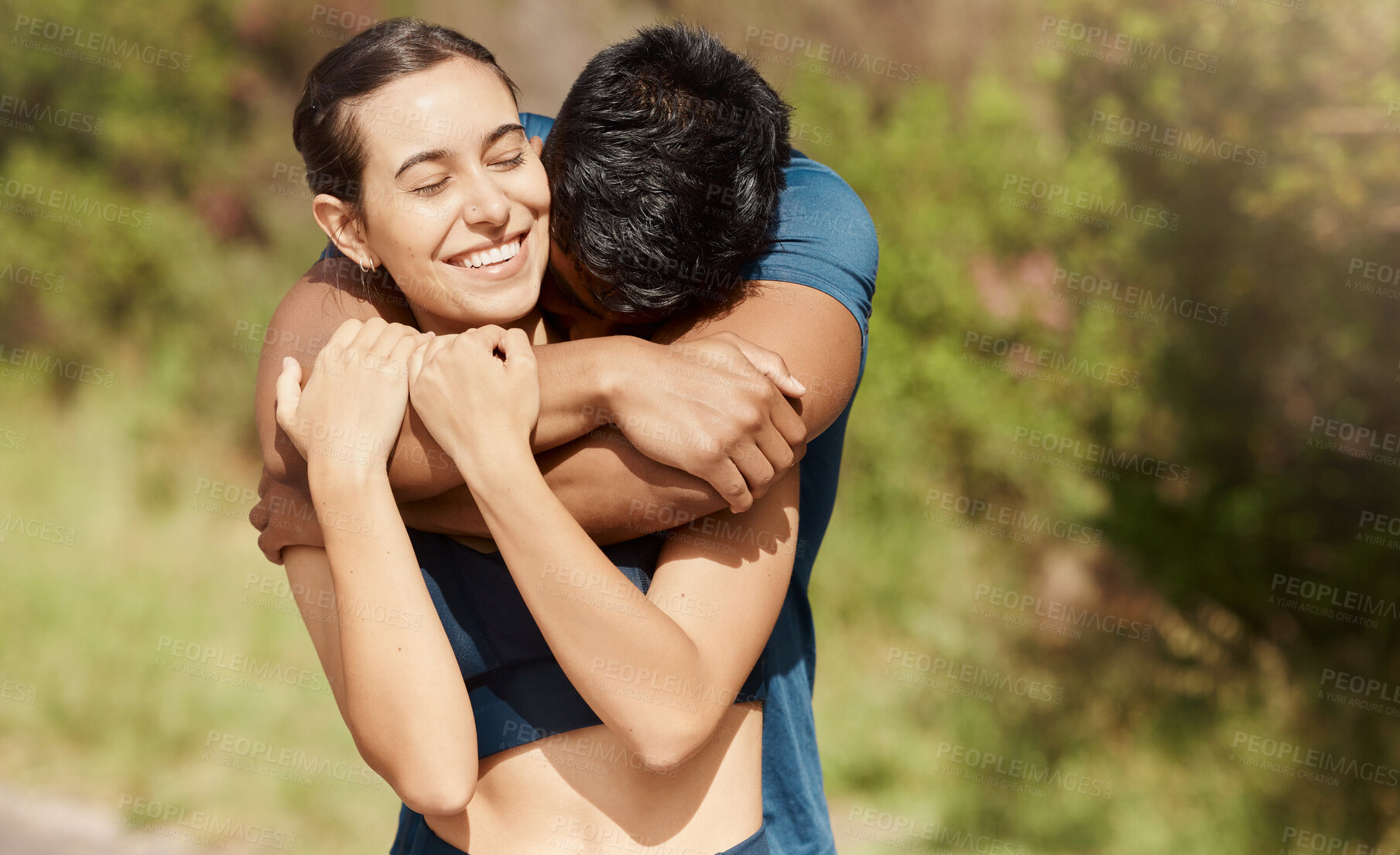 Buy stock photo Affectionate young interracial couple taking a break from exercise and run outdoors. Loving man hugging arm around woman while motivating each other towards better health and fitness