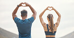 Fit young man and woman from the back gesturing heart shapes with hands while exercising together outdoors. Two athletes caring for body with regular training workout or run. Endorsing and loving a healthy active lifestyle