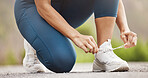 Closeup of one mixed race woman tying her shoelaces while exercising outdoors. Athlete fastening sneaker footwear for a comfortable fit and to prevent tripping while getting ready for cardio training workout or run at the park
