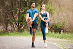 Fit young man and woman stretching legs for warmup to prevent injury while exercising together outdoors. Interracial couple and motivated athletes preparing body and muscles for training workout or run