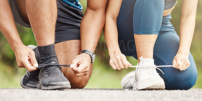 Buy stock photo Closeup of a mixed race man and woman tying their shoelaces while exercising outdoors. Hands of two athletes fastening sneaker footwear for a comfortable fit and to prevent tripping while getting ready for cardio training workout or run at the park