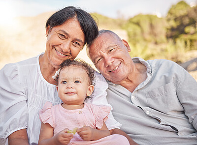 Buy stock photo Happy mixed race grandparents sitting with granddaughter on a beach. Adorable, happy, hispanic baby girl bonding with grandmother and grandfather in a garden or park outside. Baby with foster parents