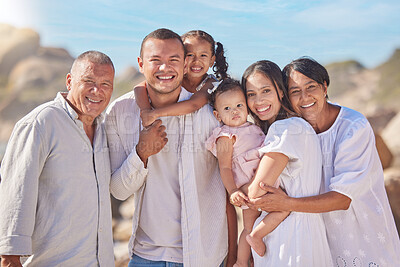 Portrait of smiling mixed race family with little girls standing together on beach. Adorable little kids bonding with mother, father, grandmother and grandfather outside