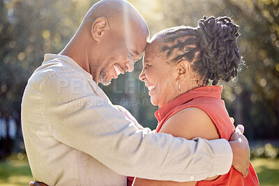 Buy stock photo Happy affectionate mature african american couple sharing an intimate moment outside at the park during summer. In love seniors smiling and embracing while spending quality time together outdoors