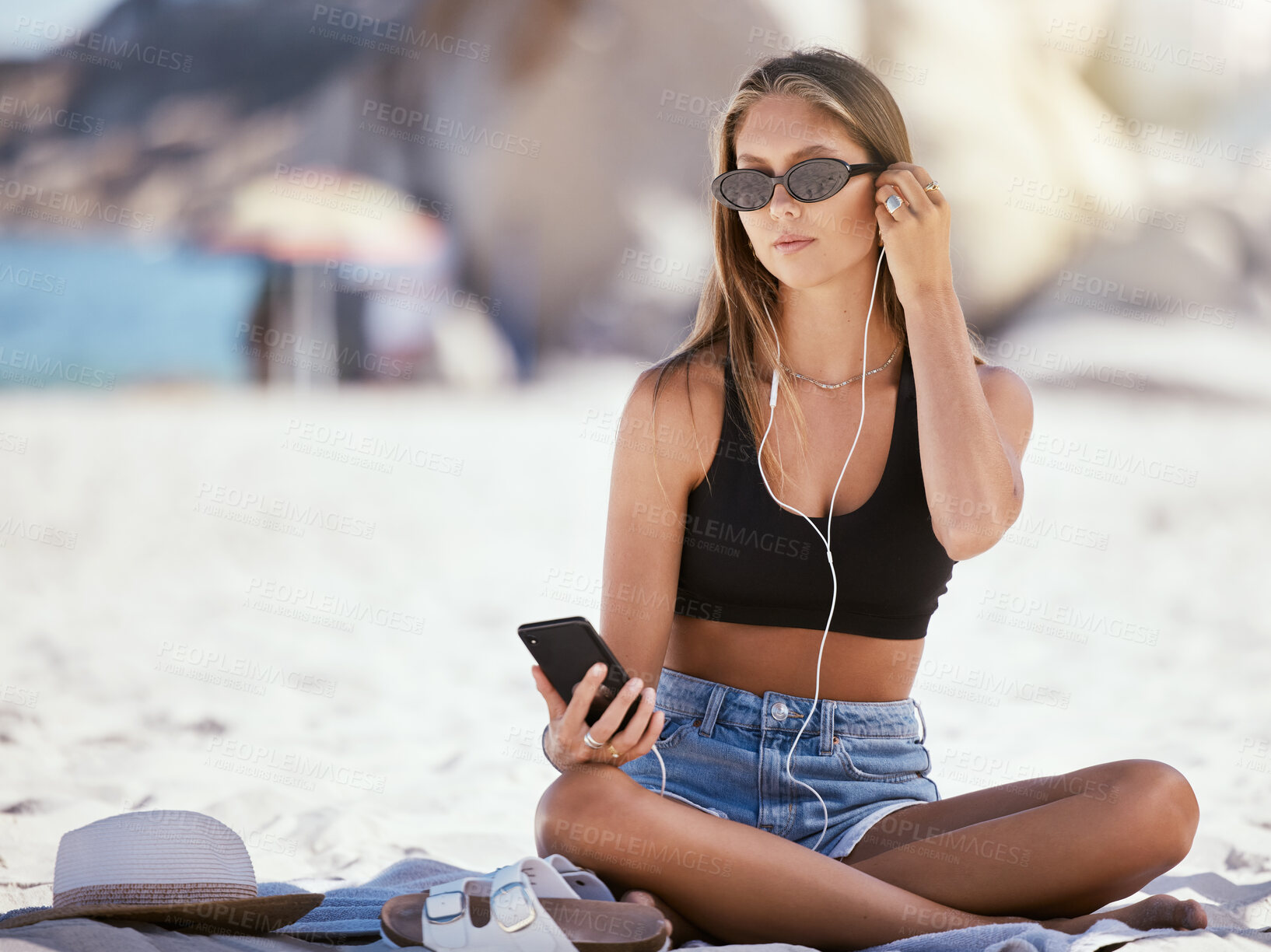 Buy stock photo Relax, woman with her smartphone and earphones on the beach listen to music. Summer vacation or holiday break, podcast or freedom and female woman with her cellphone outdoors for peace at sea