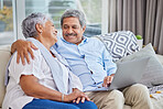 Closeup of an affectionate mixed race senior couple relaxing in their living room at home using a laptop. Hispanic man and wife  bonding on the sofa in the living room being affectionate and using a wireless device