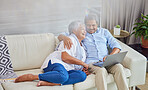 Closeup of an affectionate mixed race senior couple relaxing in their living room at home using a laptop. Hispanic man and wife  bonding on the sofa in the living room being affectionate and using a wireless device