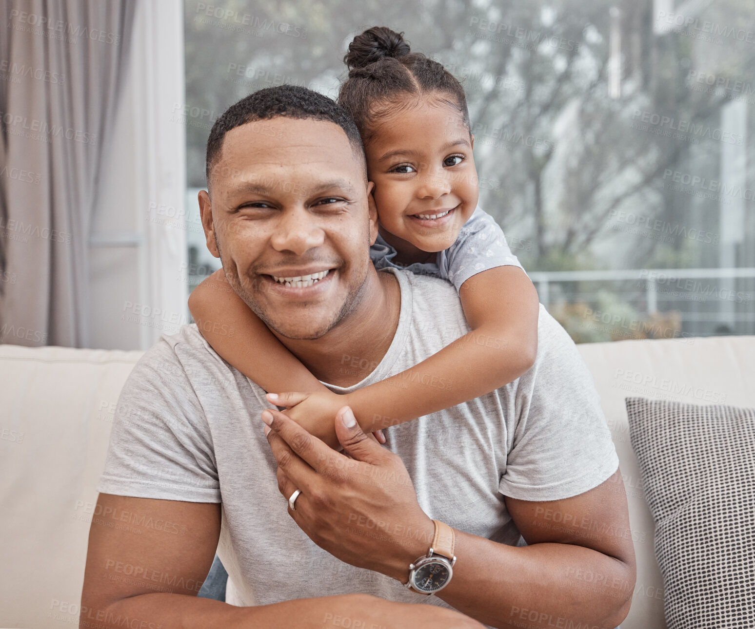 Buy stock photo Handsome young mixed race man and his cute daughter hugging on a sofa in the living room at home. Father and his girl child bonding and showing affection. A single parent and female kid in the lounge