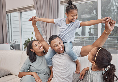 Buy stock photo Happy and affectionate young mixed race family of four sitting on a sofa in the living room at home. Married couple sitting with their two daughters in the lounge. Mom, dad and girl sibling sisters