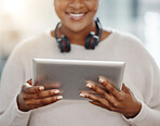 Closeup of one confident african american businesswoman browsing on a digital tablet device while working in an office. Entrepreneur planning online with smart apps