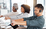 Group of call centre telemarketing agents stretching their arms while working together in an office. Hispanic male consultant taking a break to get ready to operate helpdesk for customer service and sales support