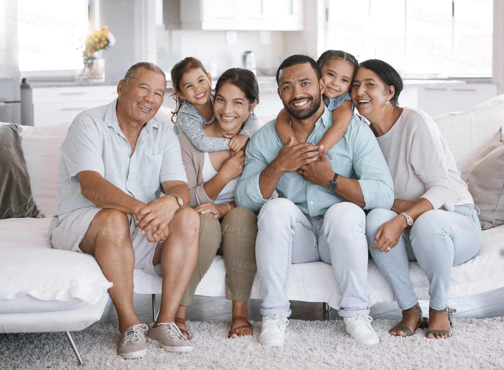 Buy stock photo Happy and content hispanic family smiling while relaxing and sitting on the couch together at home. Cheerful and carefree little brother and sister enjoying time with their parents and grandparents