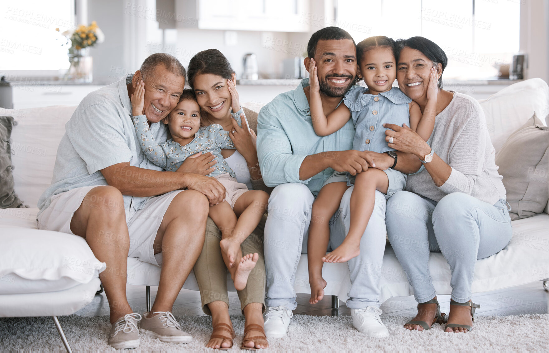 Buy stock photo Happy and content hispanic family smiling while relaxing and sitting on the couch together at home. Cheerful and carefree little brother and sister enjoying time with their parents and grandparents
