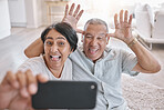 Closeup of an affectionate senior couple taking selfies while relaxing in the living room at home. Mixed race couple having fun taking photos in the lounge at home
