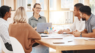 Mature caucasian businesswoman leading a presentation with her colleagues during a meeting in an office boardroom. Businesspeople planning strategy together. Team brainstorming with their manager in a creative startup agency