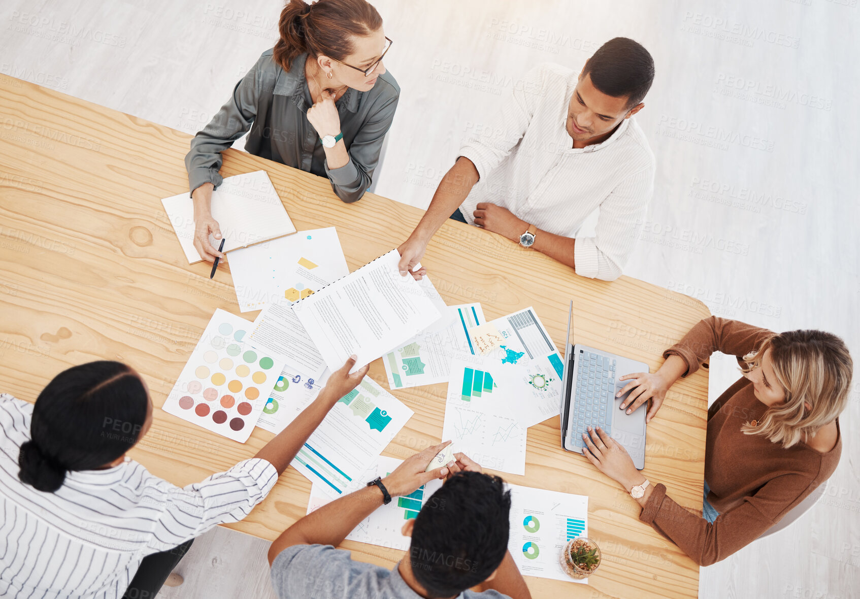 Buy stock photo Diversity, top view of colleagues planning and brainstorming together with paperwork on a table at their workplace. Collaboration or teamwork, ideas or strategy and coworkers working with lens flare