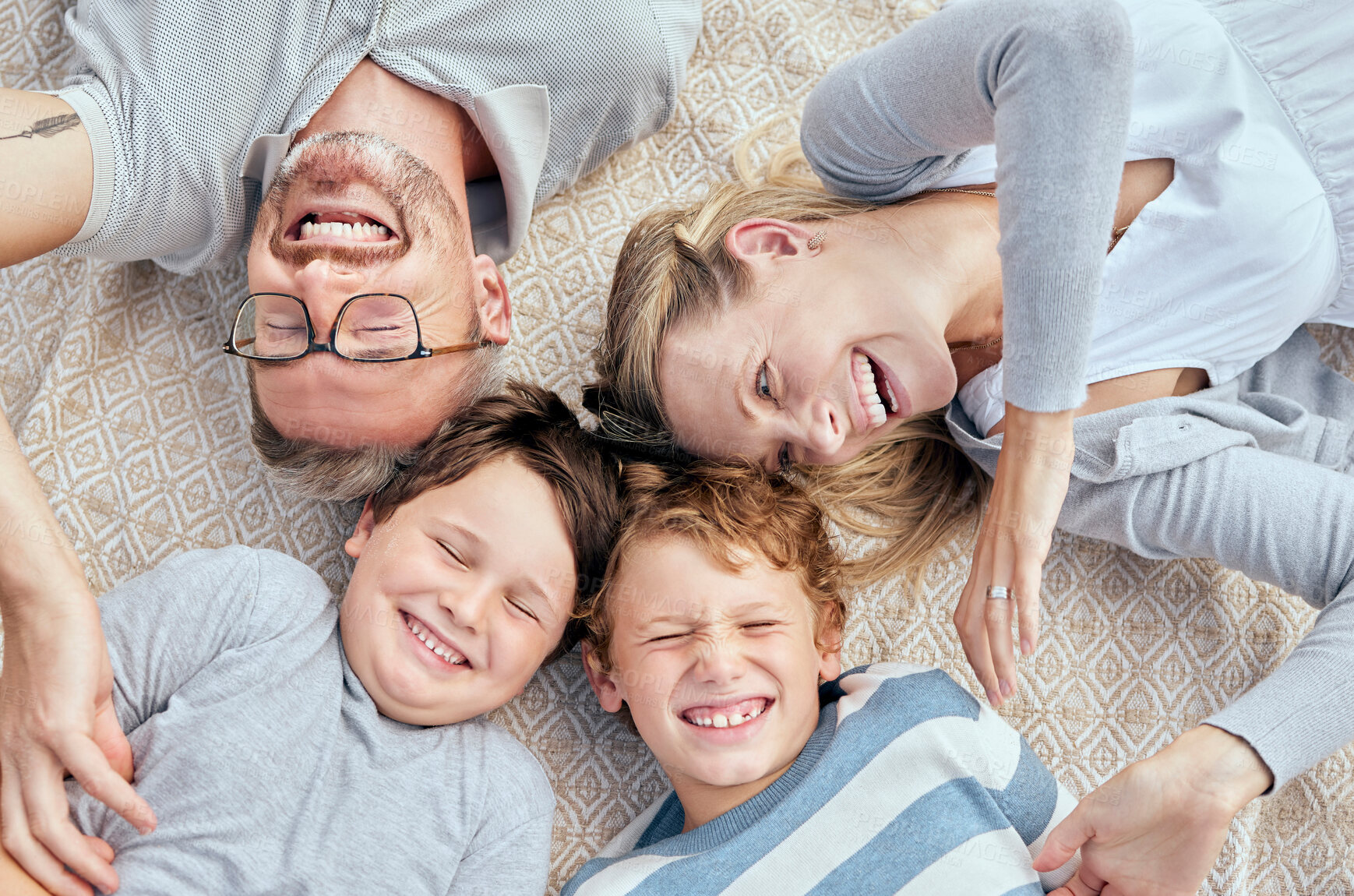 Buy stock photo Carefree loving parents from above tickling and teasing their cute little laughing sons. Happy caucasian family of four relaxing and playing together. Cheerful kids spending quality time with mom and dad
