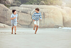 Two young caucasian boys running and playing together at the beach. Happy little brothers racing on the sand shore while having fun during a summer holiday vacation