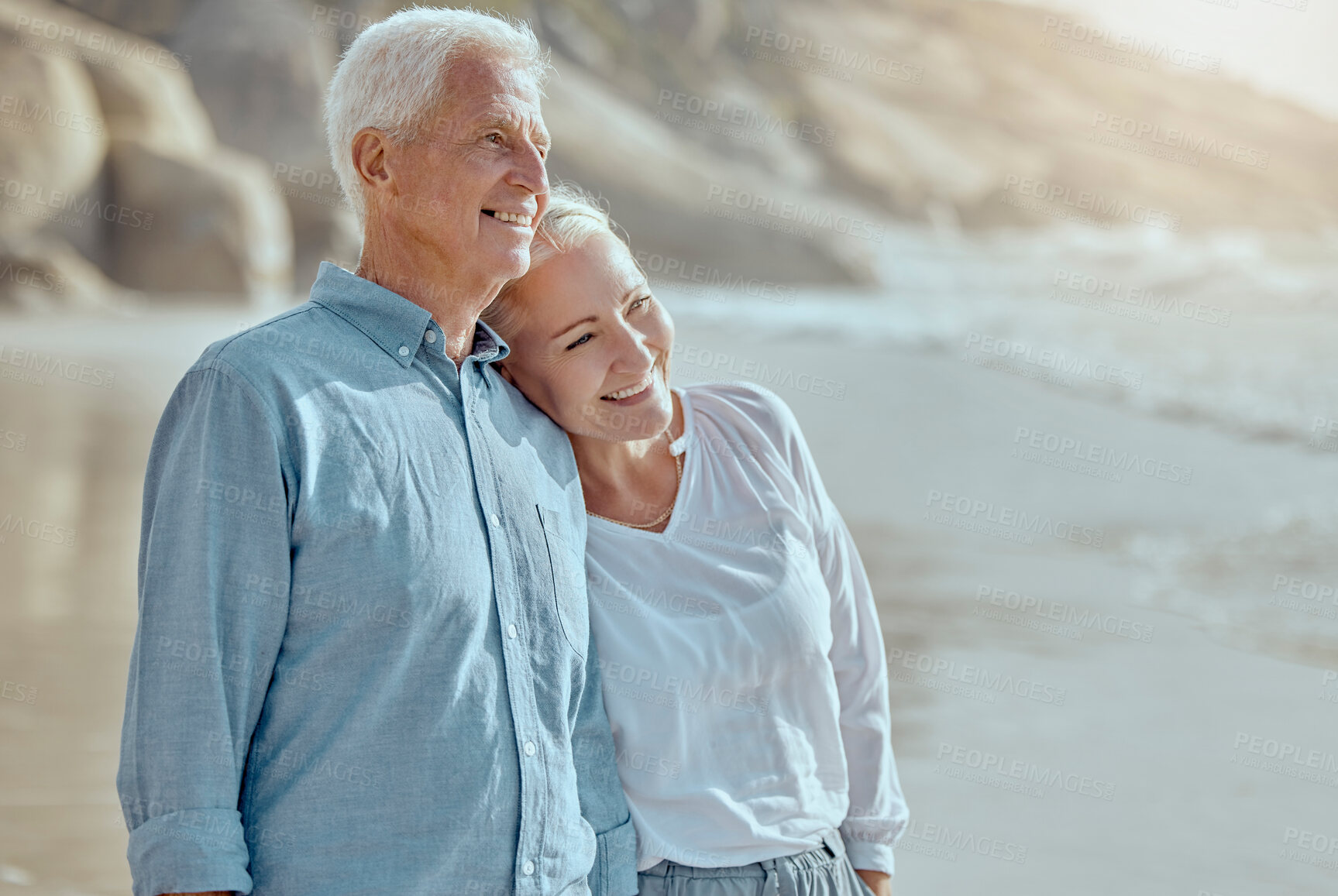 Buy stock photo A happy mature caucasian couple enjoying fresh air on vacation at the beach. Smiling retired couple hugging and embracing while bonding outside together