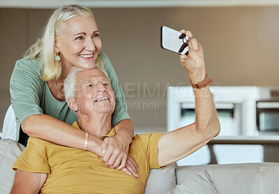 Buy stock photo Happy elderly couple bonding and enjoying retirement together. Senior caucasian man and woman being affectionate on a sofa at home  while taking selfies with a cellphone