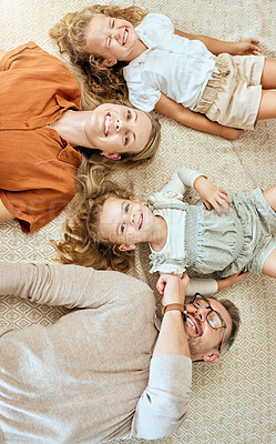 Buy stock photo A happy Caucasian family of four lying in the living room at home. Loving smiling family being affectionate on the lounge floor. Young couple bonding with their  little kids at home