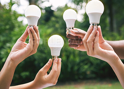 Buy stock photo Multiple hands holding lightbulbs outside in nature. Closeup of multiethnic people holding bulbs as a concept of sustainable electricity. Multiracial people holding lightbulbs