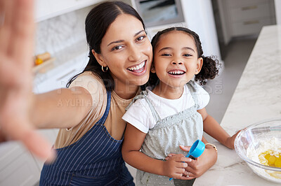 Buy stock photo Happy mother and daughter baking and taking a selfie. Young woman teaching her daughter how to bake with a bowl of batter in the kitchen at home. Smiling mother cooking with her cute little girl