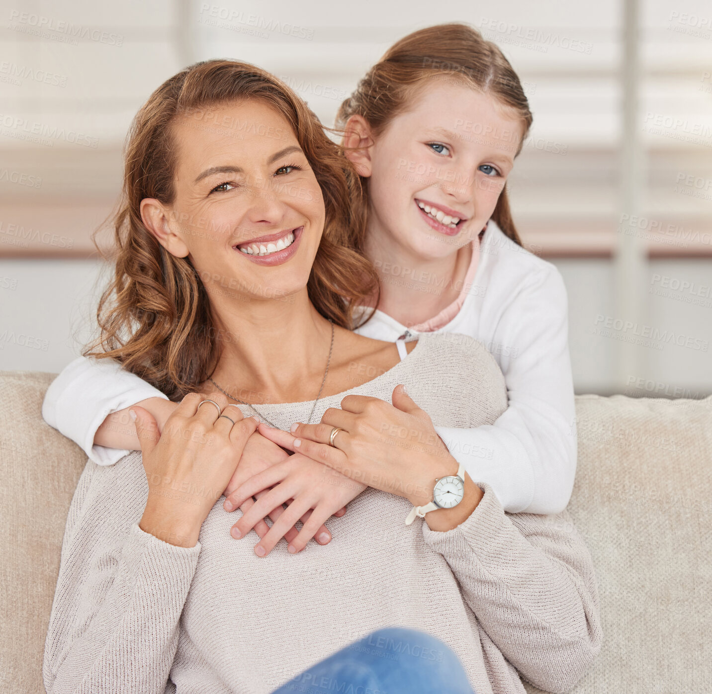 Buy stock photo Portrait of a single mother and her daughter. Adorable girl bonding with her single parent and hugging in the living room at home. Smiling woman and her affectionate kid enjoying free weekend time 