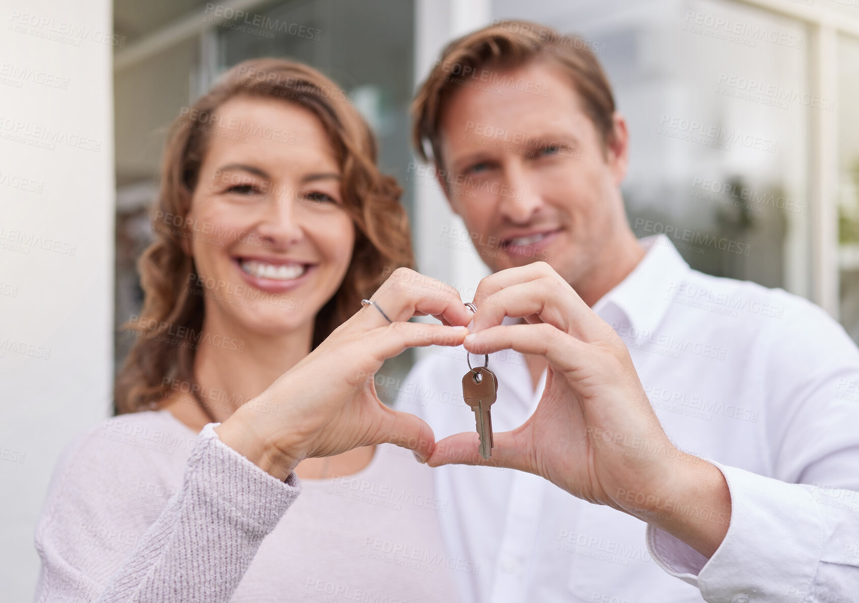 Buy stock photo Closeup hands of happy married couple holding up new house keys with a heart shape hand gesture. Man and woman holding keys to new house or apartment. 