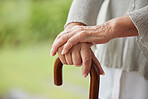 Senior disabled woman hands holding a cane outside in a nursing home park. Closeup of elderly lady holding a walking aid outdoors, relaxing at a healthcare facility on the sunny day