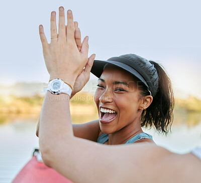 Buy stock photo Two friends sharing high five and celebrating their success while being active outdoors. Cheerful woman out kayaking and motivating her partner while enjoying a water activity on a lake in summer