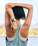 One active woman from the back stretching arms and triceps by pulling elbow towards spine while exercising outdoors. Female athlete doing warmup to prepare body and muscles for training workout or run